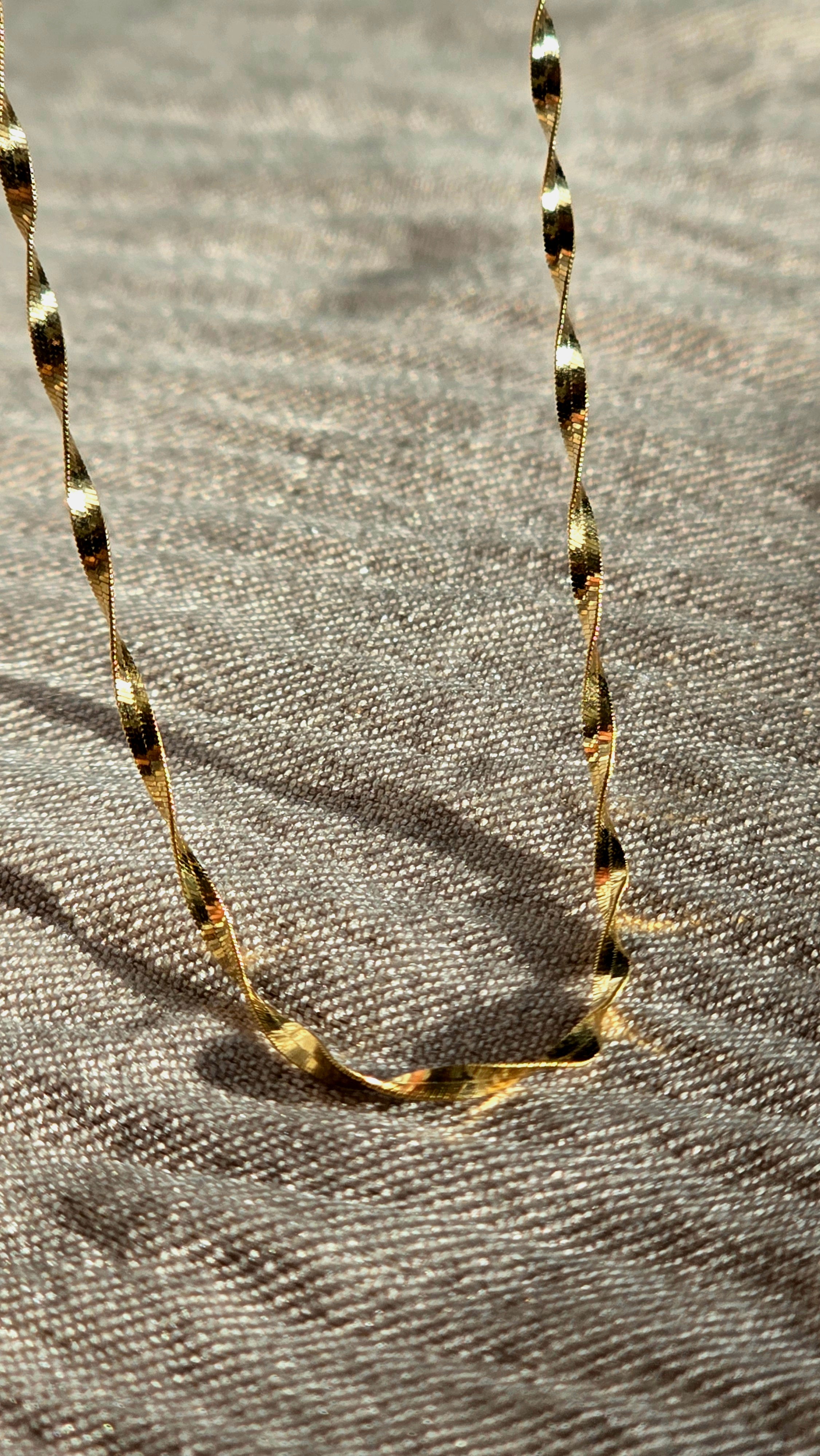 Gold chain necklace on a textured gray surface