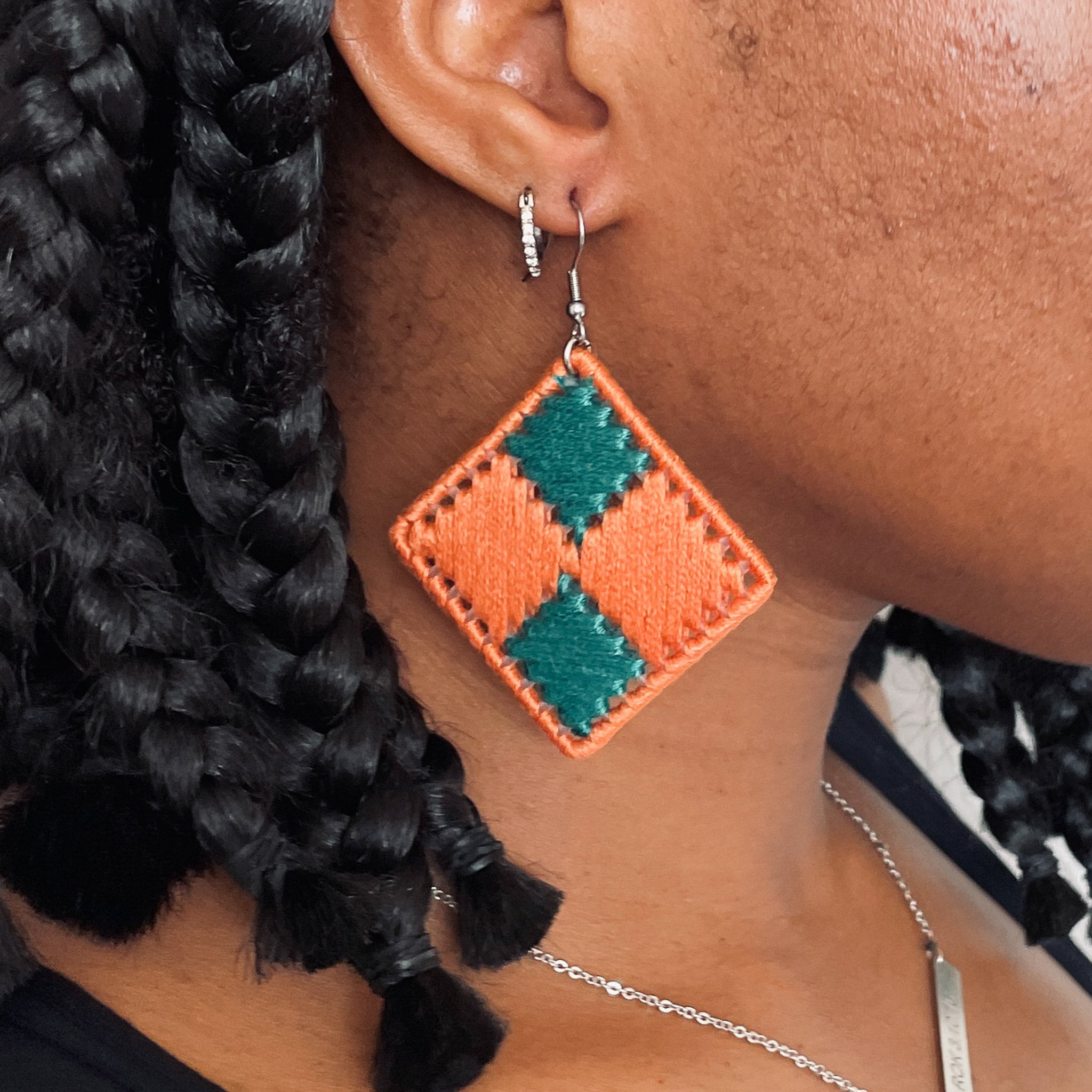 Model wearing the orange and green Benni earrings, highlighting the geometric design