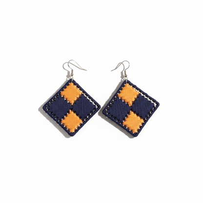 Pair of square earrings with orange and navy checkered pattern on a white background