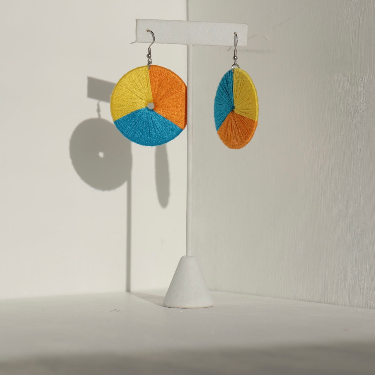 The Bode earrings in a mix of bold colors, displayed on a jewelry stand with soft lighting