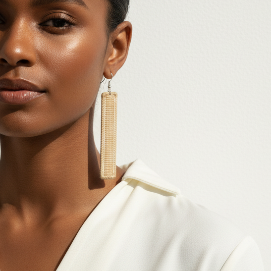 Woman wearing a white top with long earrings against a neutral background