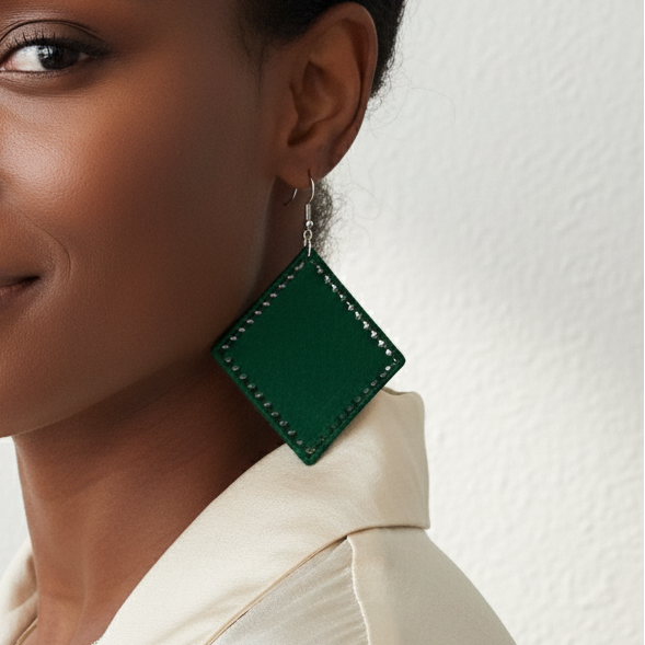 Woman wearing green earrings against a plain background