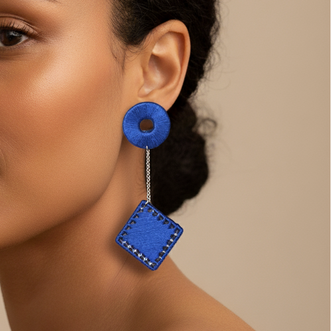 Woman wearing blue earrings against a beige background