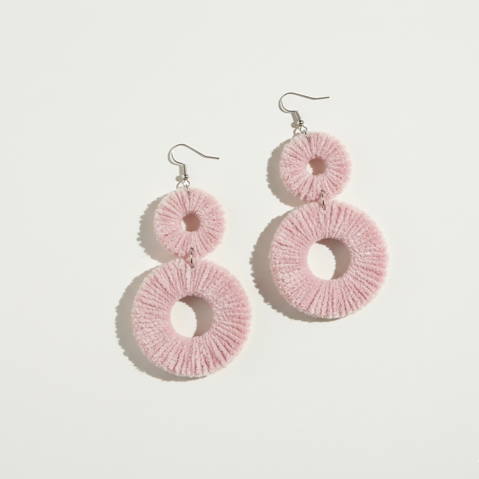 Pink circular earrings on a light gray background