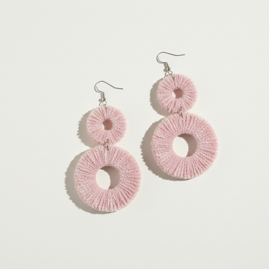 Pink circular earrings on a light gray background