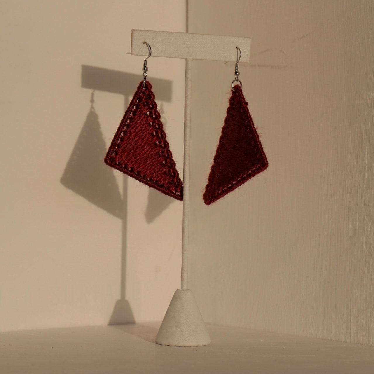 The Kofi earrings in maroon by OlaNti Houston, a sculptural addition to any collection