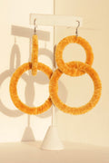 The Valente earrings in yellow displayed on a jewelry stand, highlighting their circular shape
