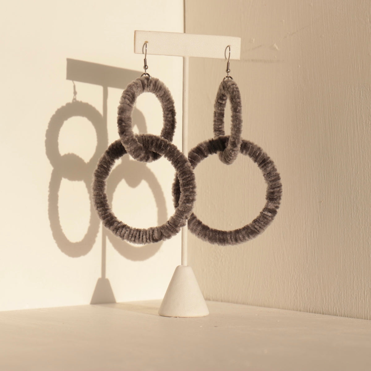 The Valente statement earrings in black displayed on a jewelry stand with soft lighting
