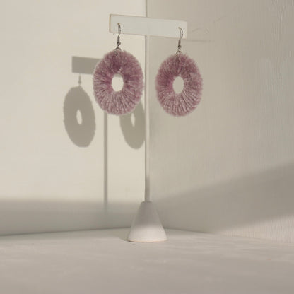 The Vinny earrings in a muted pink tone, displayed elegantly on a jewelry stand