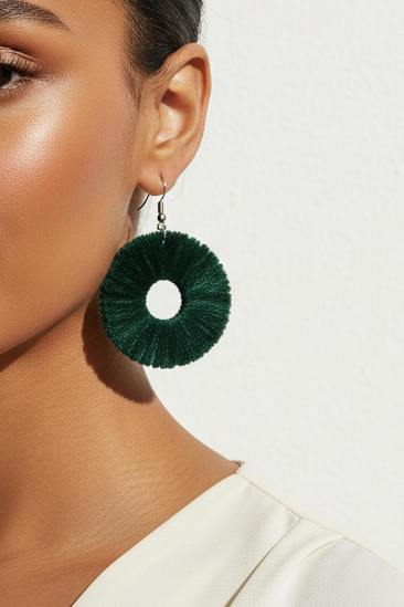 Woman wearing green earrings with a plain background
