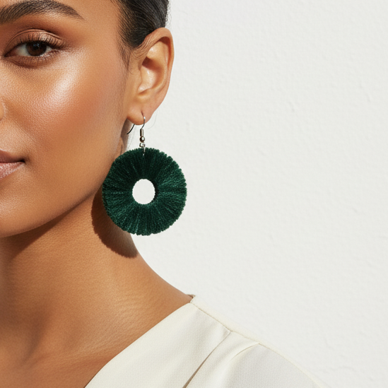 Woman wearing green earrings with a plain background