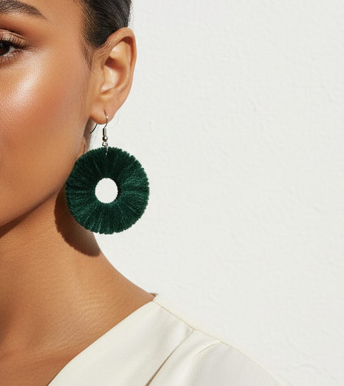 Woman wearing green earrings with a plain background
