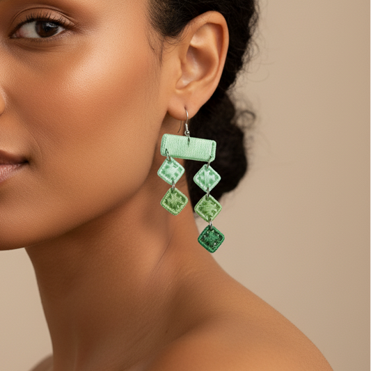 Woman wearing green earrings against a beige background